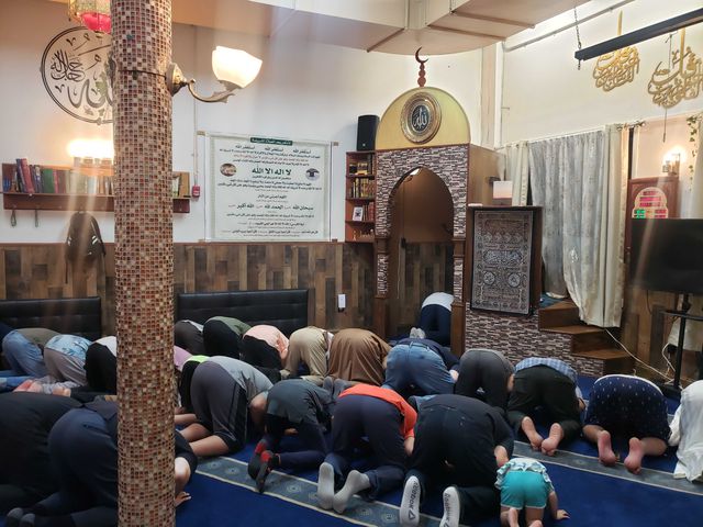 Dozens of people kneel and pray at the mosque inside the Muslim Community Center